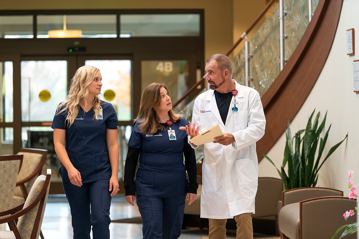 Three clinicians walking across a hospital lobby.