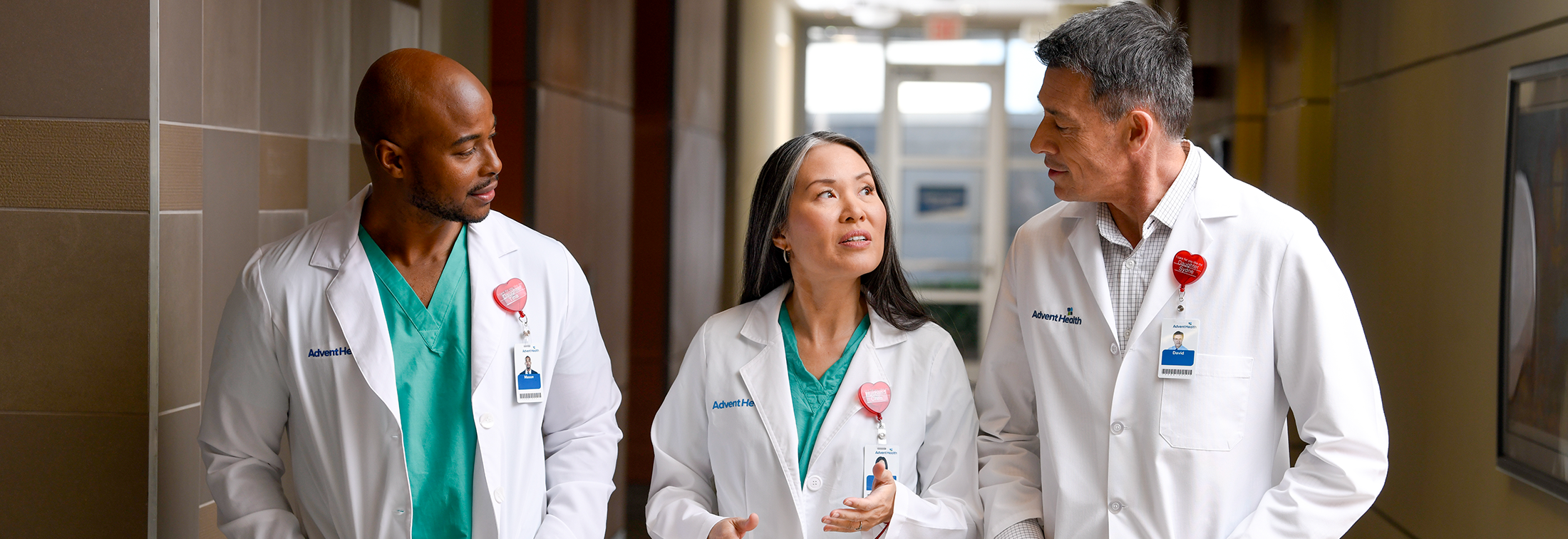 Three doctors having a discussion in a hospital hallway.