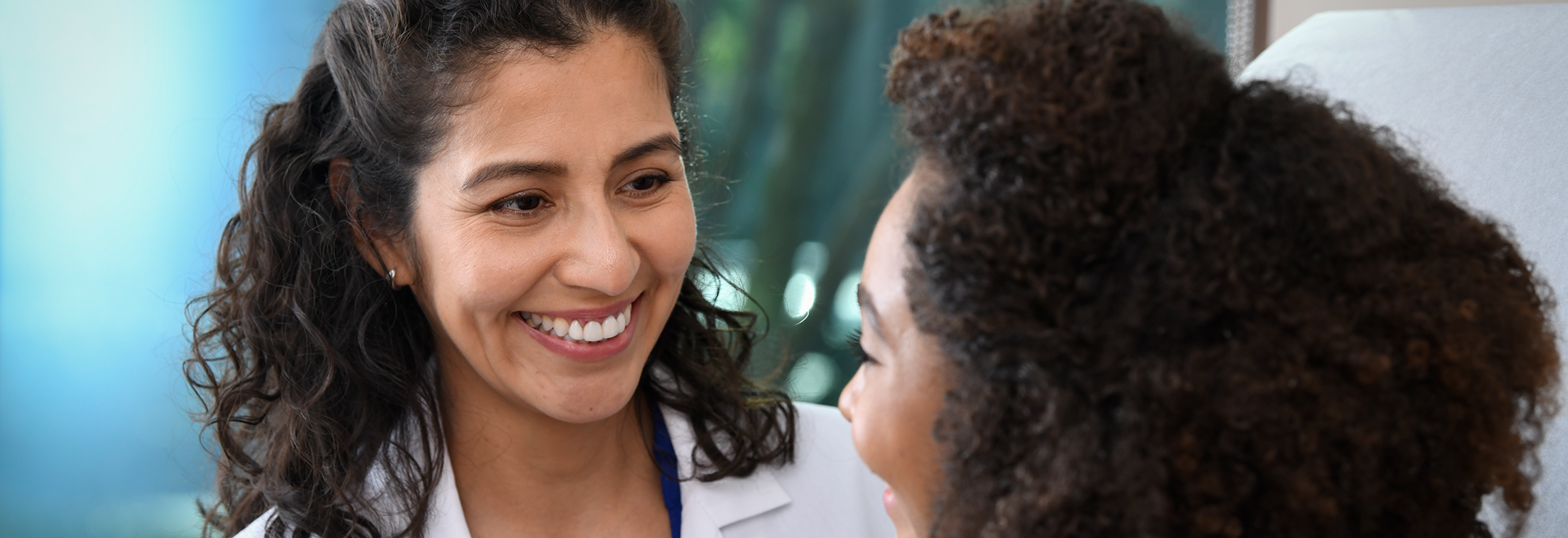 A doctor and a young person smiling during a medical consultation.